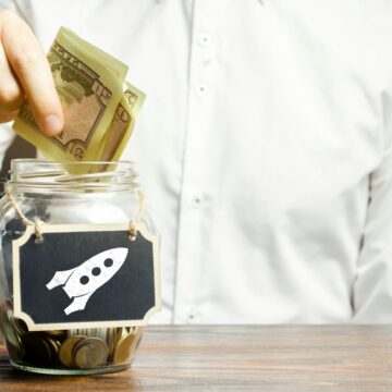 A man puts money into a startup jar. Research and development.