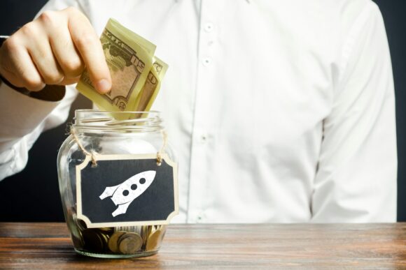 A man puts money into a startup jar. Research and development.