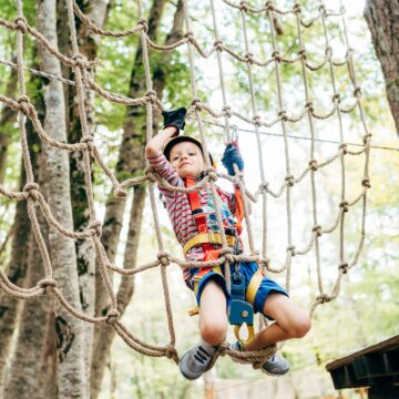 Boy climbing on a gladiator mesh in an adventure park