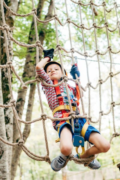 Boy climbing on a gladiator mesh in an adventure park