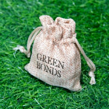 Closeup image of jute bag with the words "green bonds" on top of a green grass field.