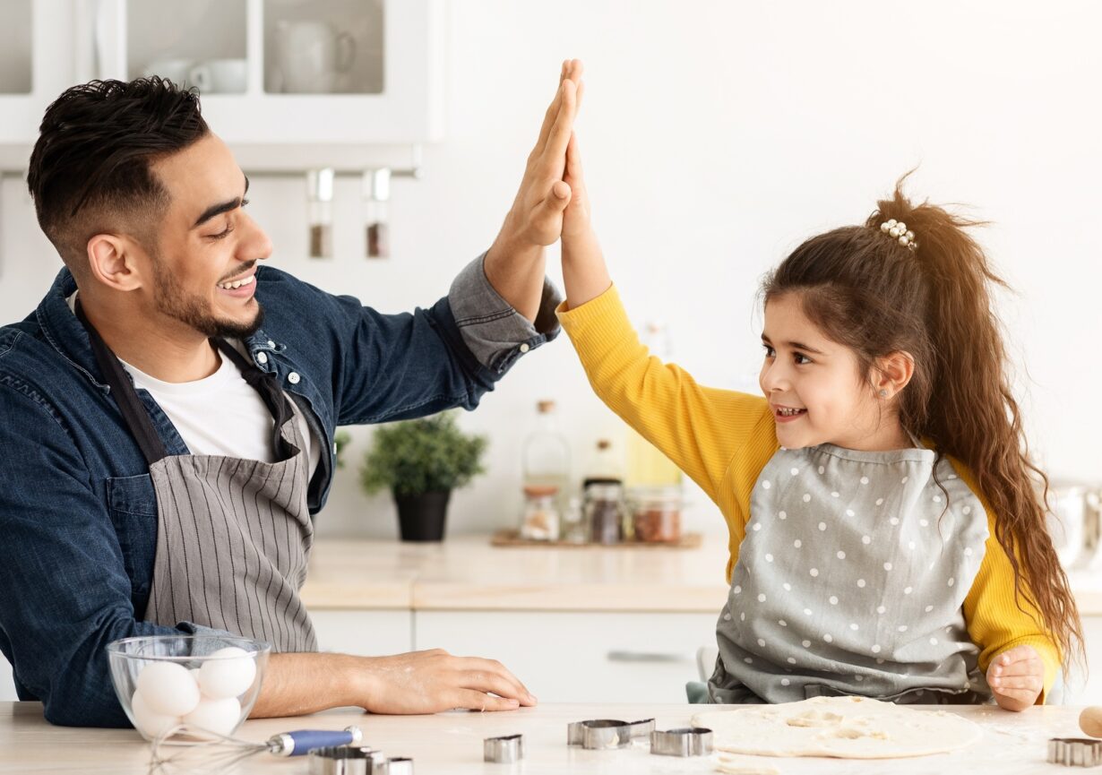 Cute Little Arab Girl And Her Dad Giving High Five In Kitchen