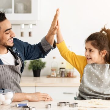 Cute Little Arab Girl And Her Dad Giving High Five In Kitchen