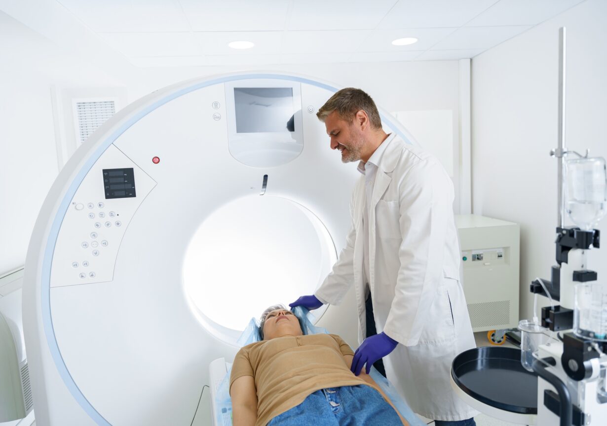 Doctor and female patient in the room of computed tomography at hospital. Healthcare concept