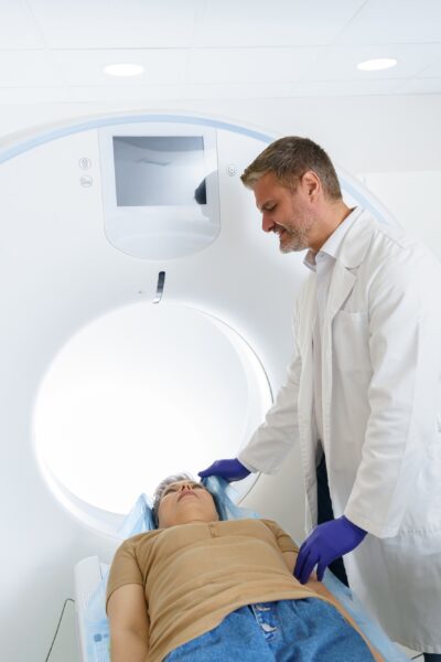 Doctor and female patient in the room of computed tomography at hospital. Healthcare concept