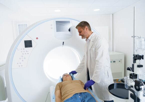 Doctor and female patient in the room of computed tomography at hospital. Healthcare concept