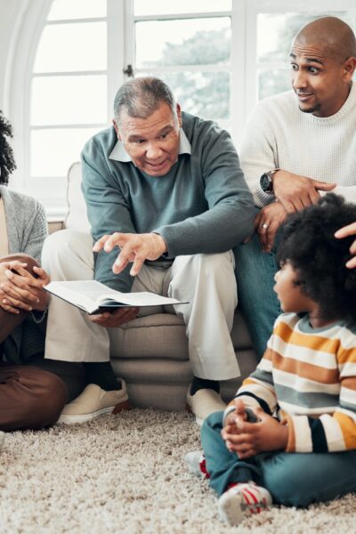 Family relax, generations with fantasy and reading book, grandparents with parents and kids at home