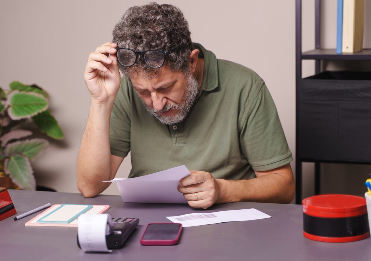 Middle-aged Man Lifting Glasses to Read a Letter