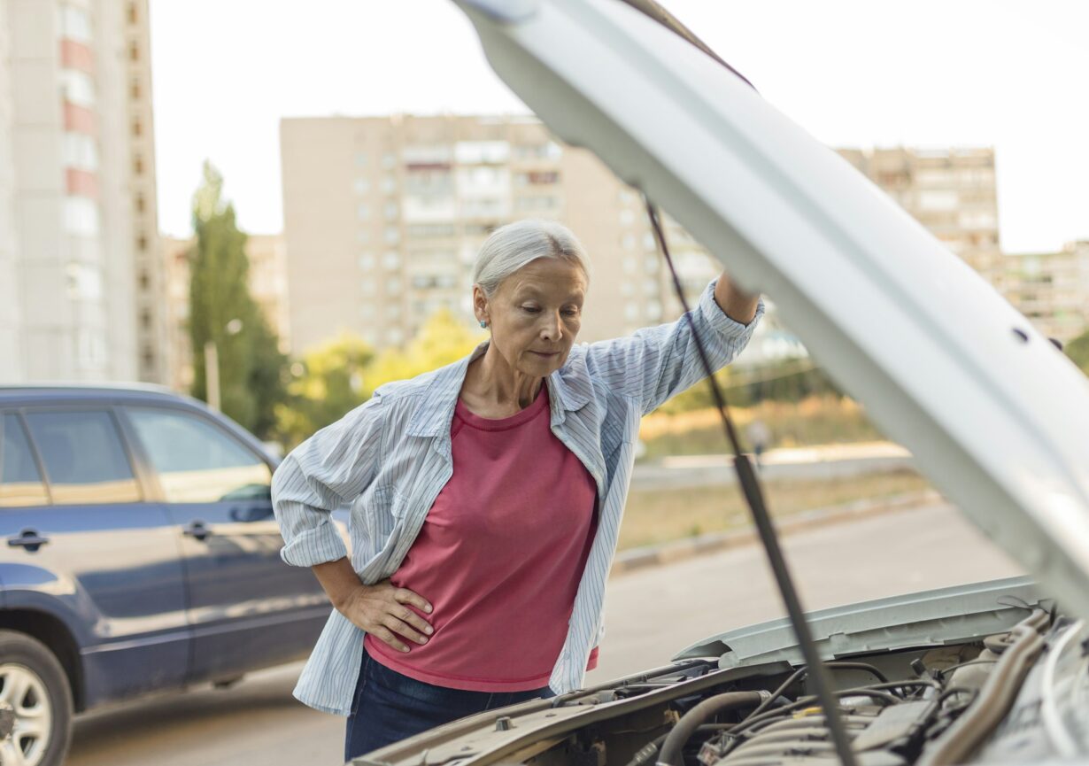 Senior woman looking at car engine