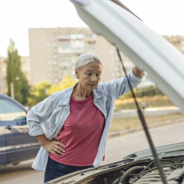 Senior woman looking at car engine