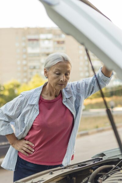 Senior woman looking at car engine