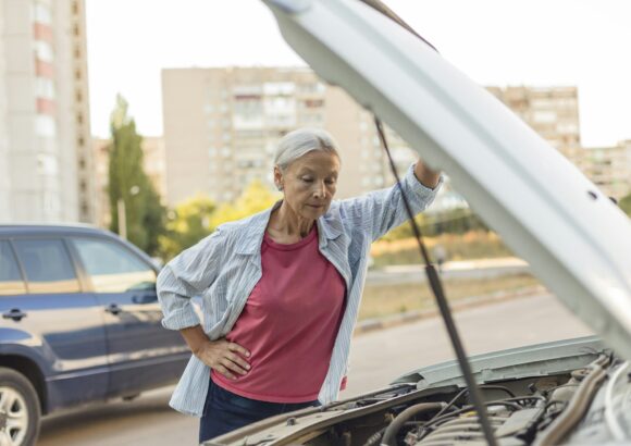 Senior woman looking at car engine