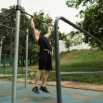 Sporty man working out in outdoor gym in park.