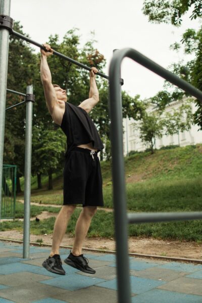 Sporty man working out in outdoor gym in park.