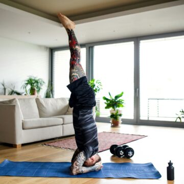 Young man doing workout exercise indoors at home, headstand