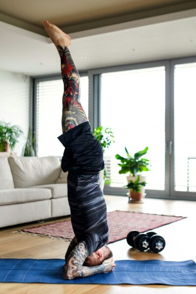 Young man doing workout exercise indoors at home, headstand